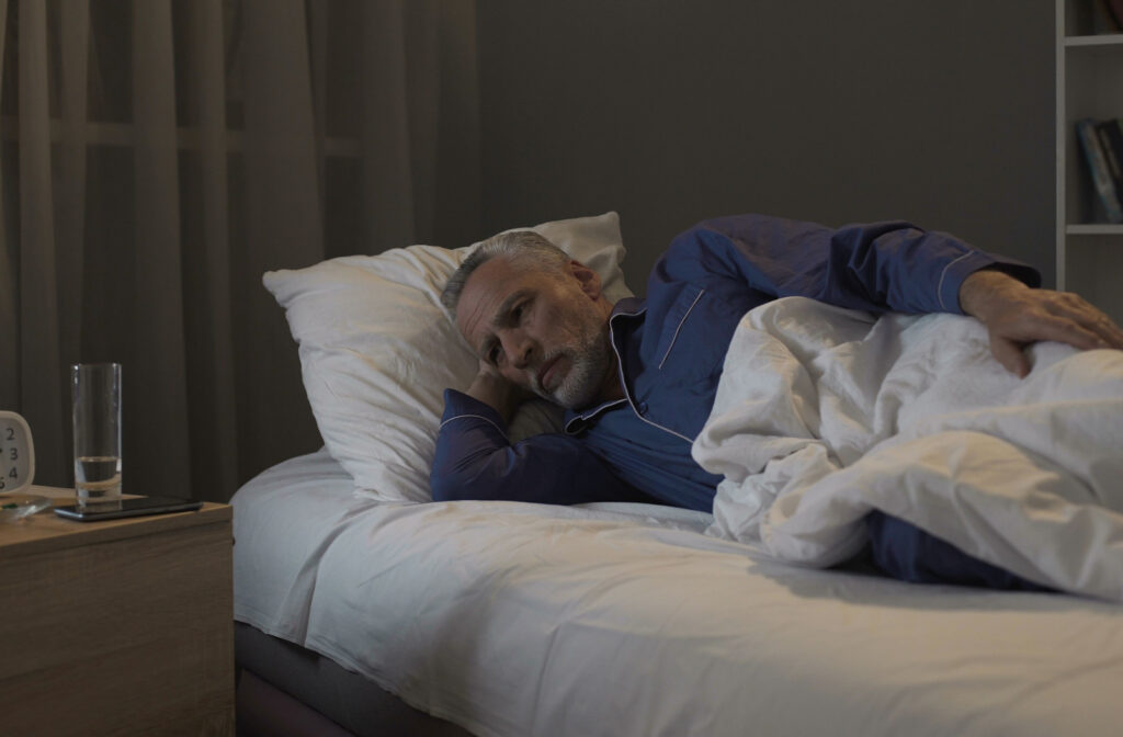 An older man in bed having trouble falling asleep due to Lewy body dementia