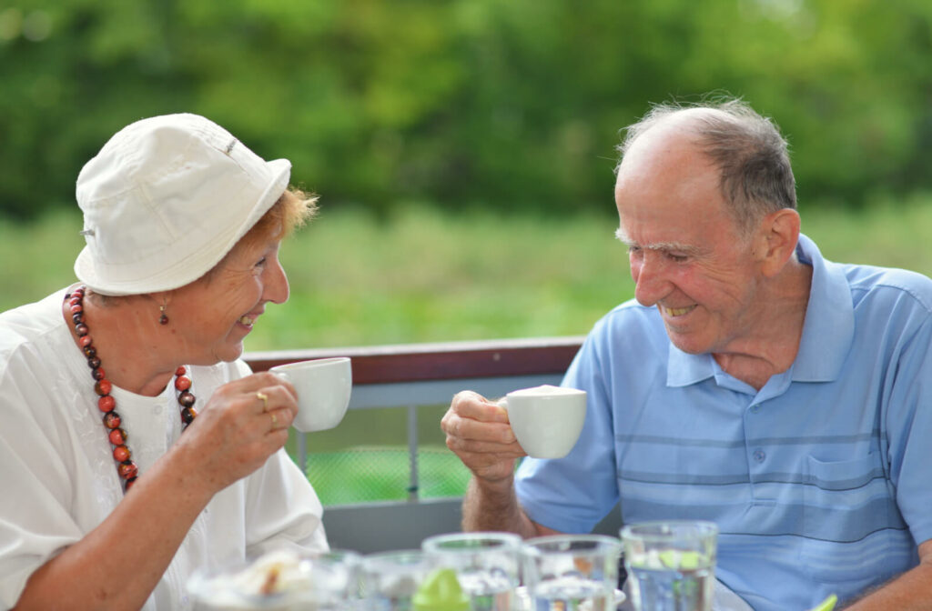 A happy senior couple enjoying a cup of coffee outdoors.