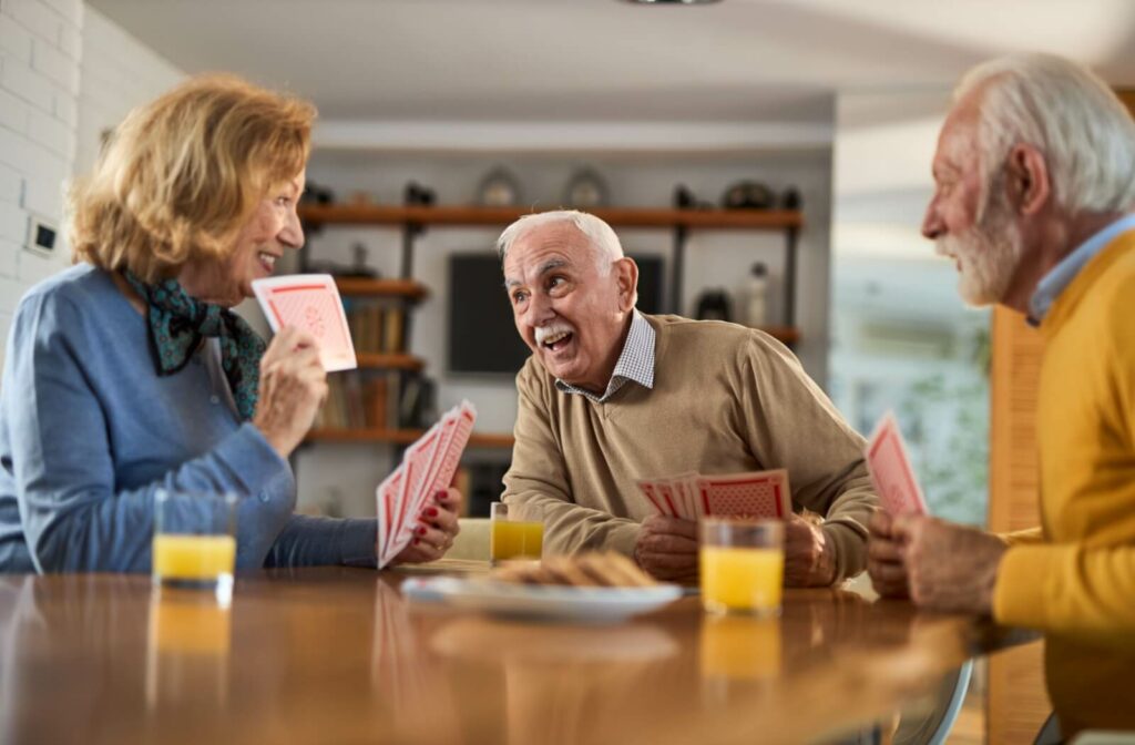 A group of seniors play cards in a senior living community.